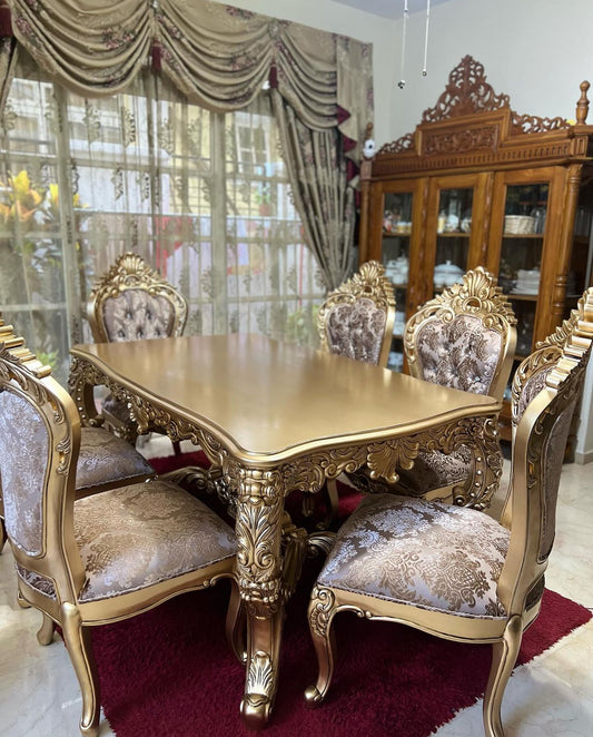 A baroque style dining room set featuring a gold-colored table with ornate legs and six matching chairs with gold upholstery.